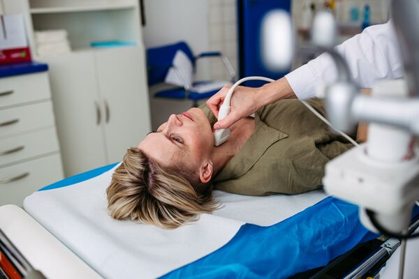 Female patient undergoing thyroid ultrasound examination